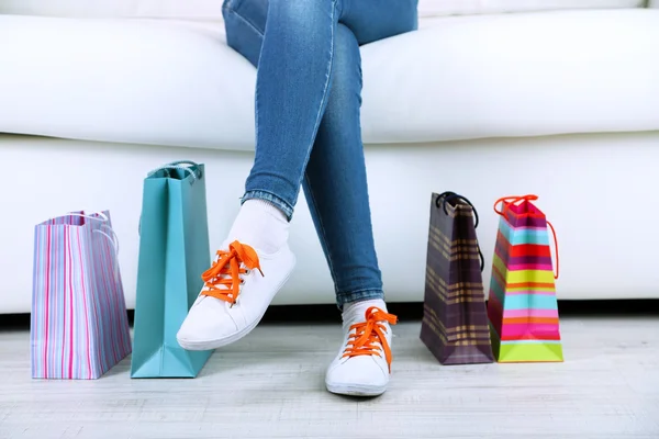 Mulher senta-se no sofá com sacos de compras close-up — Fotografia de Stock