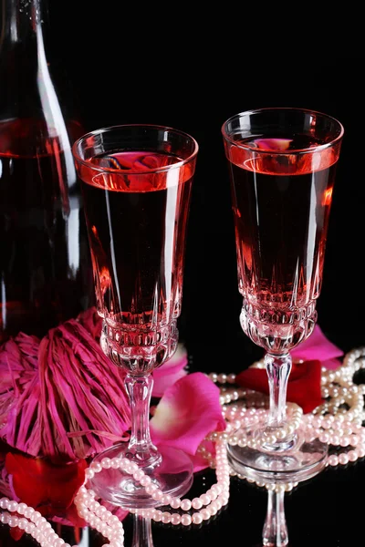 Composition with pink  wine in glasses, bottle  and  roses isolated on black background — Stock Photo, Image