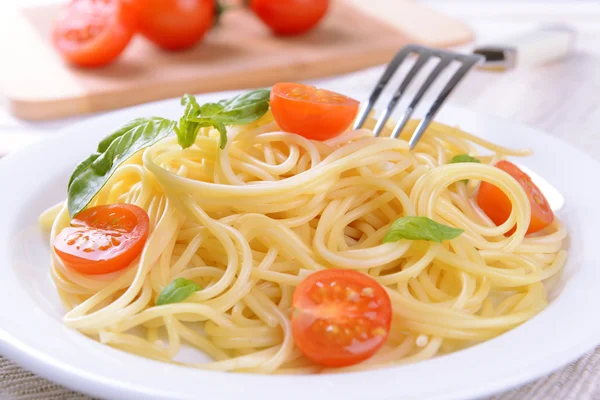 Delicious spaghetti with tomatoes on plate on table close-up — Stock Photo, Image