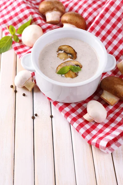 Mushroom soup in white pot, on napkin, on wooden background — Stock Photo, Image