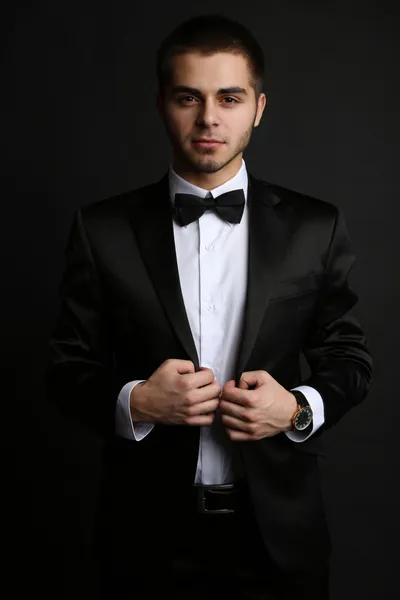 Schöner junger Mann im Anzug auf dunklem Hintergrund — Stockfoto