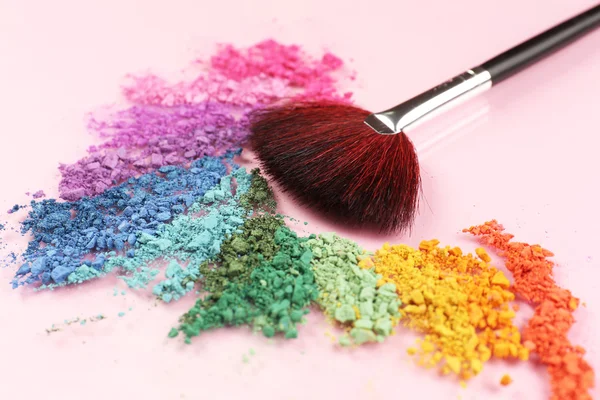 Rainbow crushed eyeshadow and professional make-up brush on pink background — Stock Photo, Image