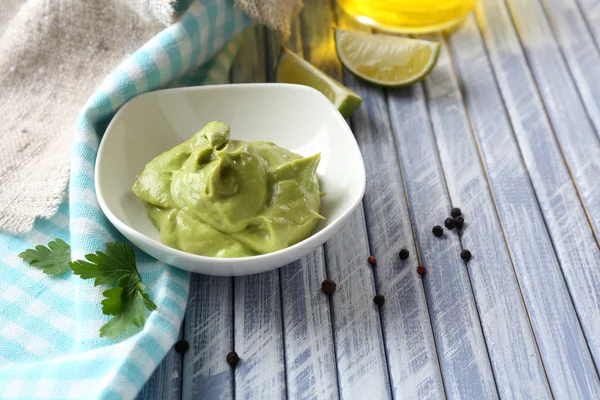 Fresh guacamole in bowl on wooden table — Stock Photo, Image