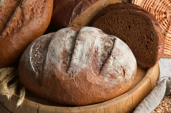 Житній хліб на дерев'яній підставці на плетеному фоні — стокове фото
