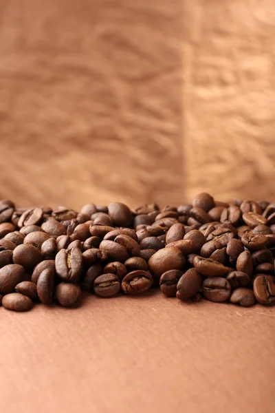 Grãos de café na mesa sobre fundo marrom — Fotografia de Stock
