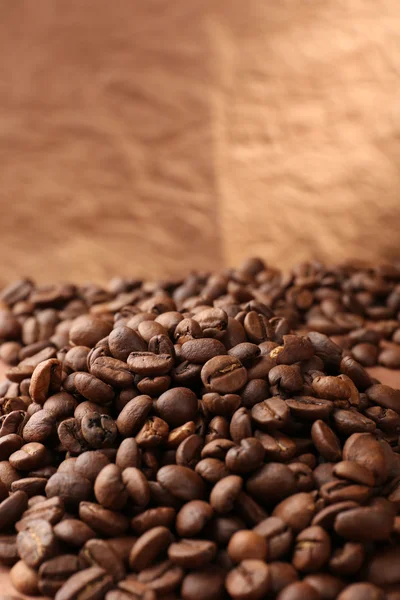 Kaffeebohnen auf Tisch auf braunem Hintergrund — Stockfoto