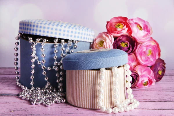 Dekorativa lådor med pärlor och blommor på bordet på ljus bakgrund — Stockfoto