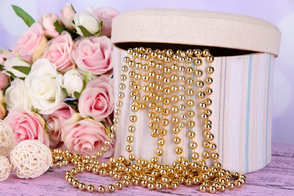 Scatola decorativa con perline e fiori sul tavolo su sfondo luminoso — Foto Stock