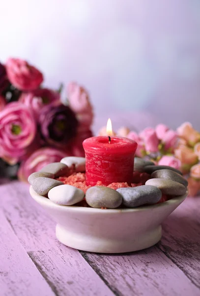 Composizione con pietre termali, candele e fiori su tavolo di legno a colori, su sfondo chiaro — Foto Stock