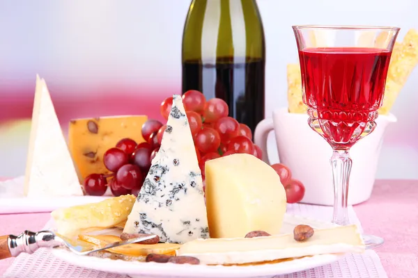 テーブルの上に並べられたチーズプレート、ブドウとワイングラス、ライトの背景 — ストック写真