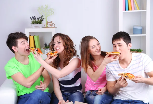 Група молодих друзів їдять піцу у вітальні на дивані — стокове фото