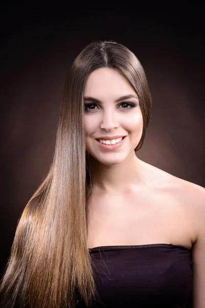 Beautiful young woman with long hair on dark brown background — Stock Photo, Image