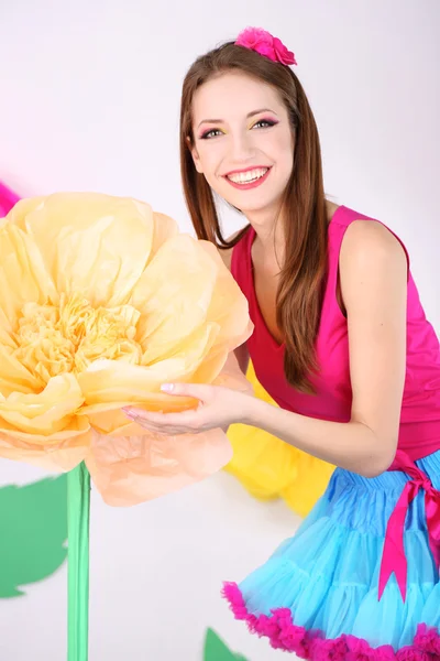 Büyük çiçek dekoratif arka planda tutan adi eteğin içinde güzel bir genç kadın — Stok fotoğraf