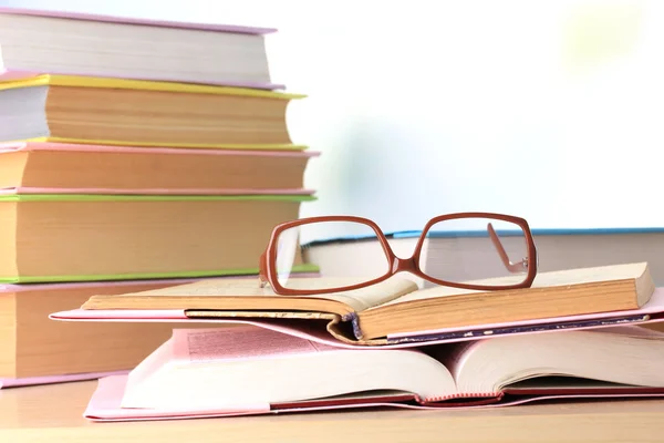 Samenstelling met glazen en boeken, op tafel, op lichte achtergrond — Stockfoto