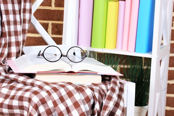 Composición con gafas y libros, sobre silla, sobre armario y fondo de pared — Foto de Stock