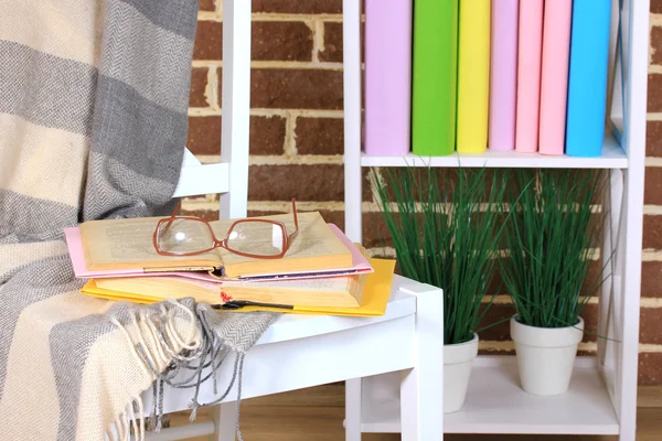 Sammansättning med glasögon och böcker, på stol, på skåpet och väggen bakgrund — Stockfoto