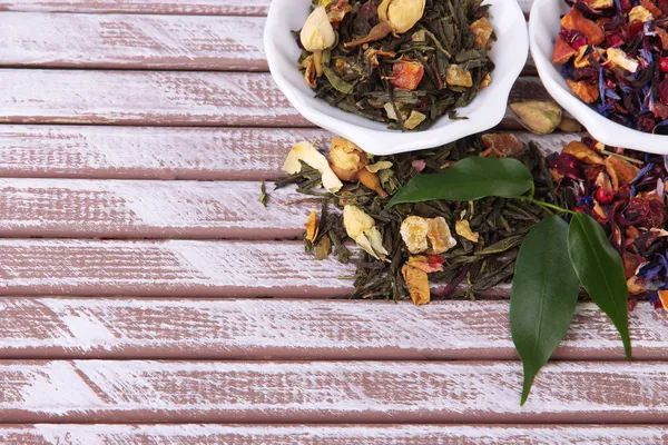Aromatischer trockener Tee in Schalen auf Holzgrund — Stockfoto