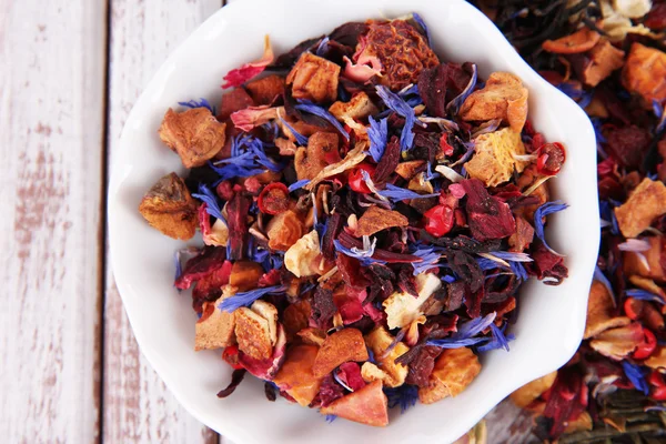 Aromatischer trockener Tee in Schale auf Holzgrund — Stockfoto