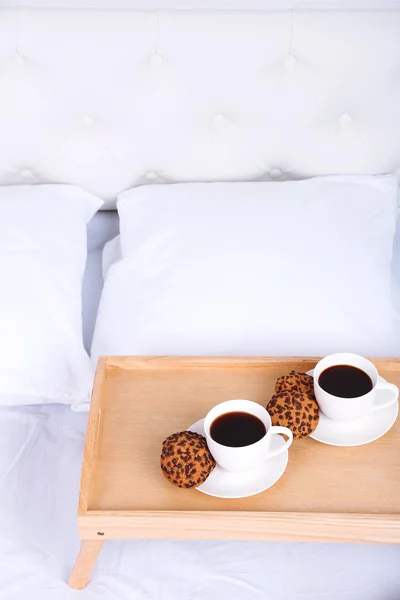 Cups of coffee on comfortable soft bed with pillows — Stock Photo, Image