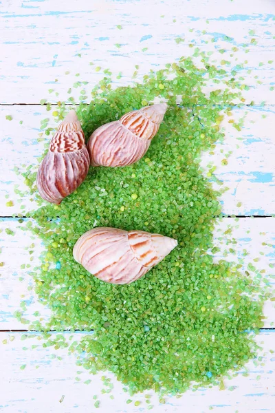 Sea salt crystals with sea shells on color wooden background — Stock Photo, Image