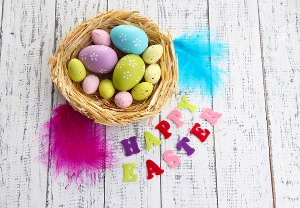 Huevos de Pascua en el nido y signo sobre fondo de madera color — Foto de Stock