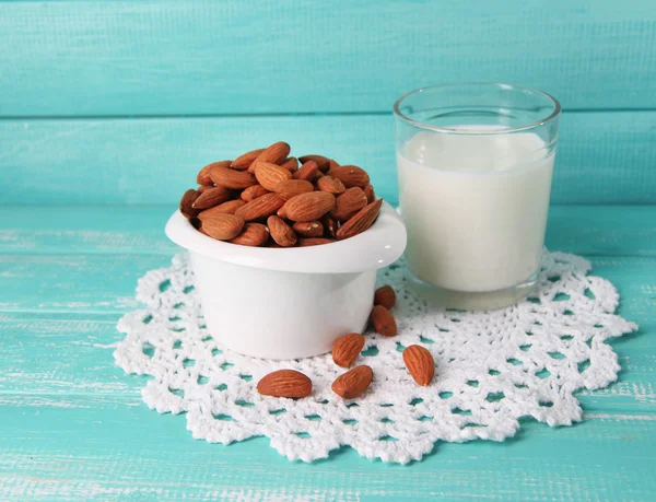 Susu almond dalam gelas dengan almond dalam mangkuk, pada warna latar belakang kayu — Stok Foto