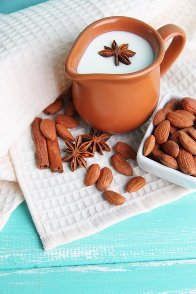 Susu almond dalam kendi dengan almond dalam mangkuk, pada warna latar belakang kayu — Stok Foto