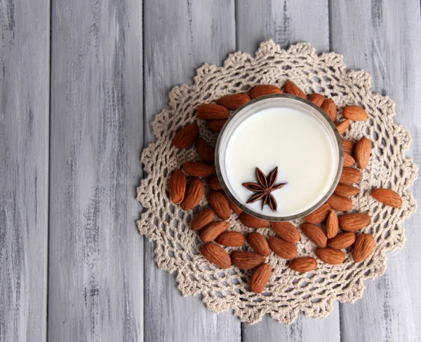 Leche de almendras en vaso con almendras, sobre fondo de madera de color —  Fotos de Stock