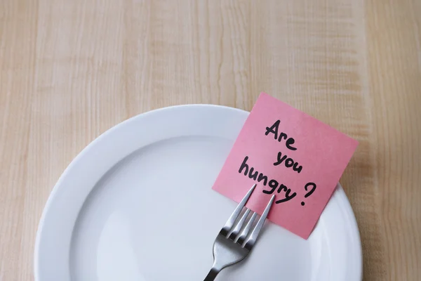 Note paper with message  attached to fork, on plate, on wooden background — Stock Photo, Image