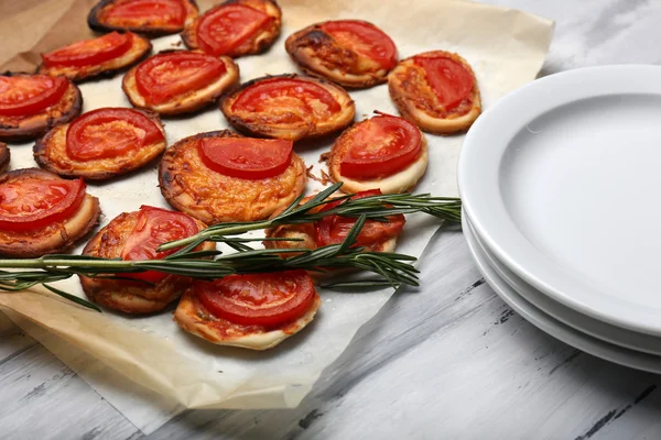 Malé pizzy na pečícím papírem zblízka — Stock fotografie