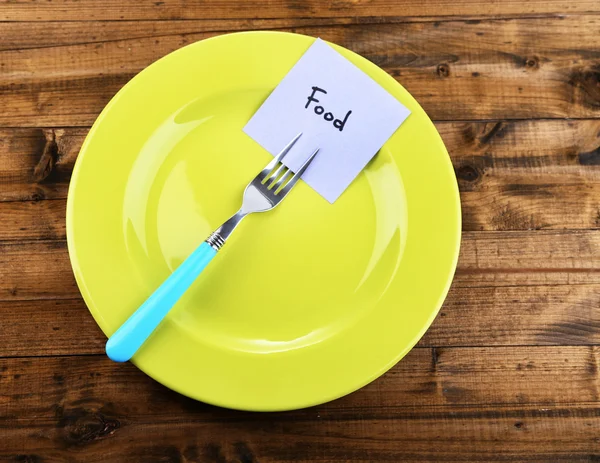 Note paper with message  attached to fork, on plate, on color wooden background — Stock Photo, Image