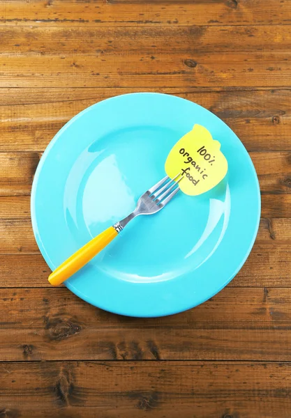 Note paper with message  attached to fork, on plate, on color wooden background — Stock Photo, Image