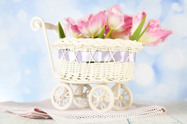 Hermosos tulipanes en cesta de mimbre decorativa, sobre mesa de madera, sobre fondo claro — Foto de Stock