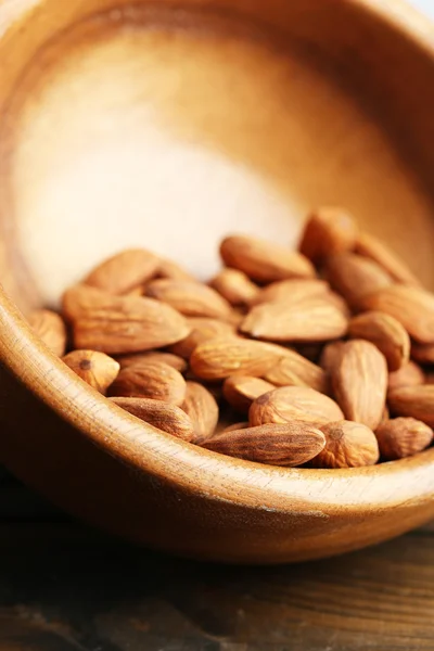 Almendras en tazón sobre fondo de madera de color — Foto de Stock