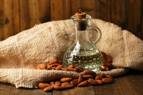 Bottle with almonds oil on color wooden background — Stock Photo, Image