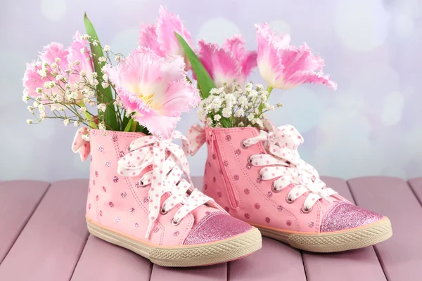 Hermosos zapatos de goma con flores en el interior en la mesa de madera, sobre fondo claro — Foto de Stock