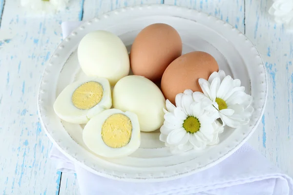 Gekochte Eier auf Teller auf farbigem Holzhintergrund — Stockfoto