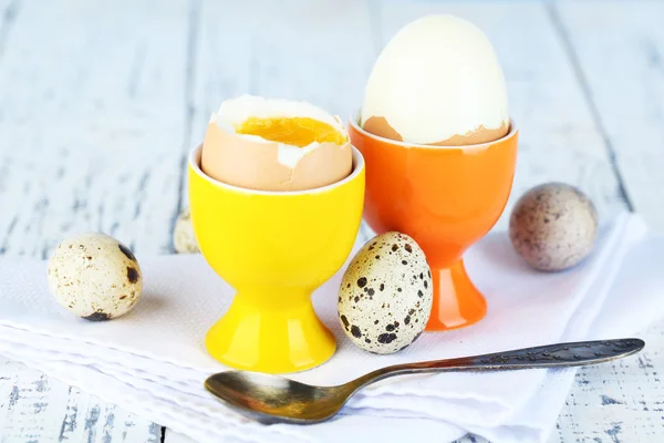 Huevos cocidos en sartén y taza de huevo sobre fondo de madera de color — Foto de Stock