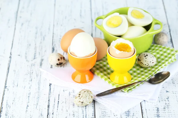 Gekookte eieren in een pan en eggcup op een houten achtergrond kleur — Stockfoto