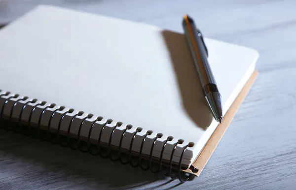Notizbuch mit Stift auf farbigem Holzhintergrund — Stockfoto
