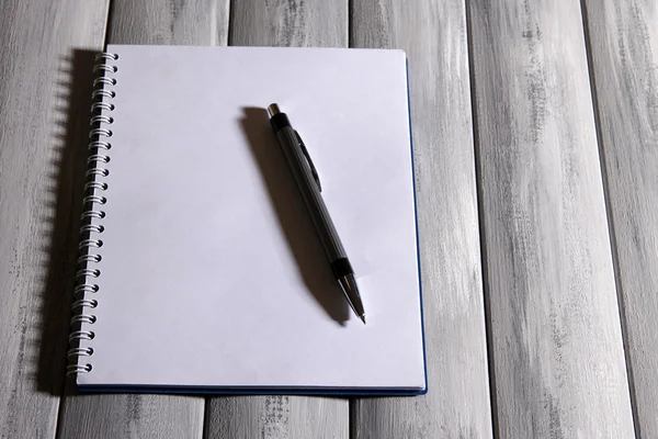 Ноутбук с ручкой на фоне цвета дерева — стоковое фото