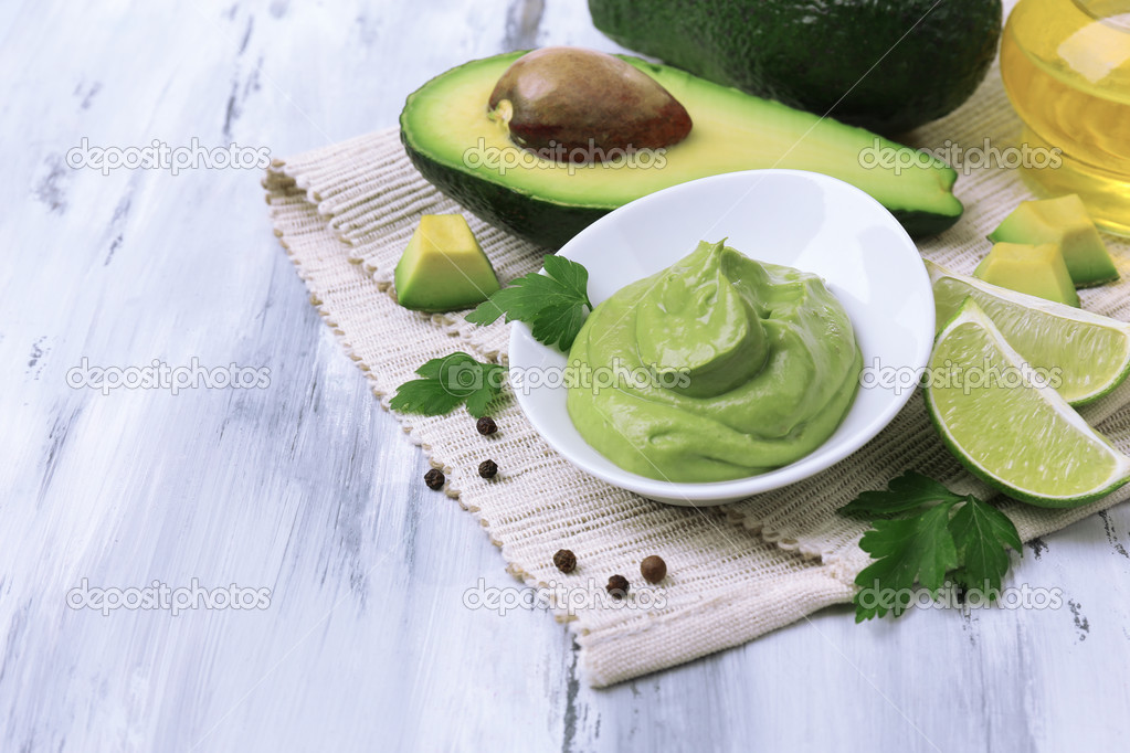 Fresh guacamole in bowl on wooden table