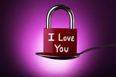 Gümüş kaşık mor zemin üzerine yapılan aşk asma kilit