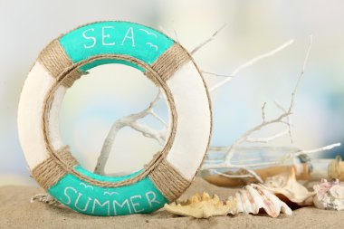 Lifebuoy ve deniz kabukları üzerinde açık renkli kum üzerinde