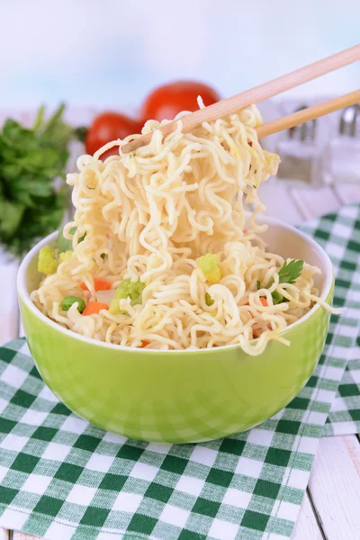 Νόστιμο στιγμιαία noodles με λαχανικά σε μπολ στο τραπέζι επάνω ελαφρύς υπόβαθρο — Φωτογραφία Αρχείου