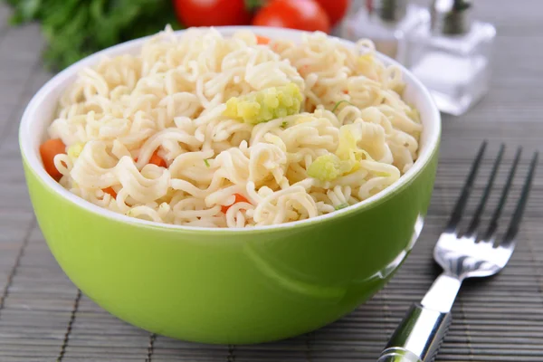 Leckere Instant-Nudeln mit Gemüse in Schüssel auf dem Tisch in Großaufnahme — Stockfoto