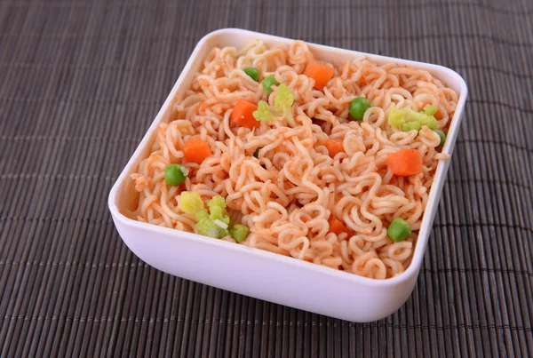 Tasty instant noodles with vegetables in bowl on table close-up — Stock Photo, Image