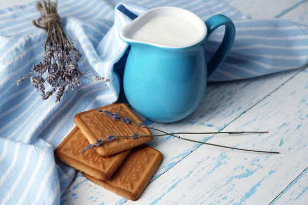 Yogurt fatto in casa in brocca e gustoso biscotto su sfondo tavolo di legno — Foto Stock