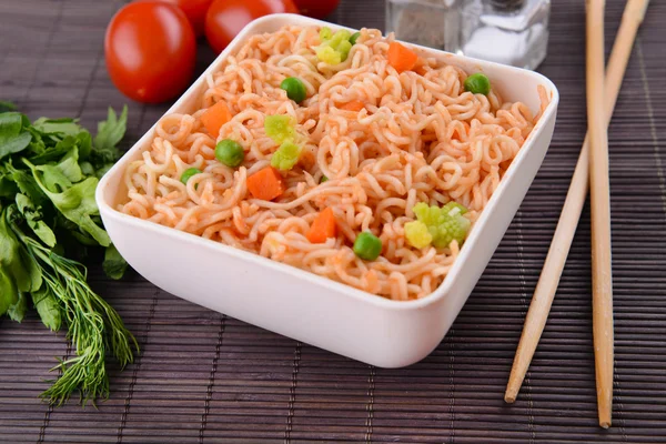 Sabrosos fideos instantáneos con verduras en un tazón en la mesa de cerca — Foto de Stock