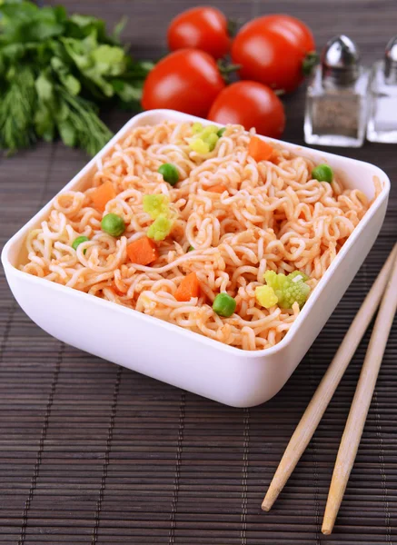 Sabrosos fideos instantáneos con verduras en un tazón en la mesa de cerca —  Fotos de Stock